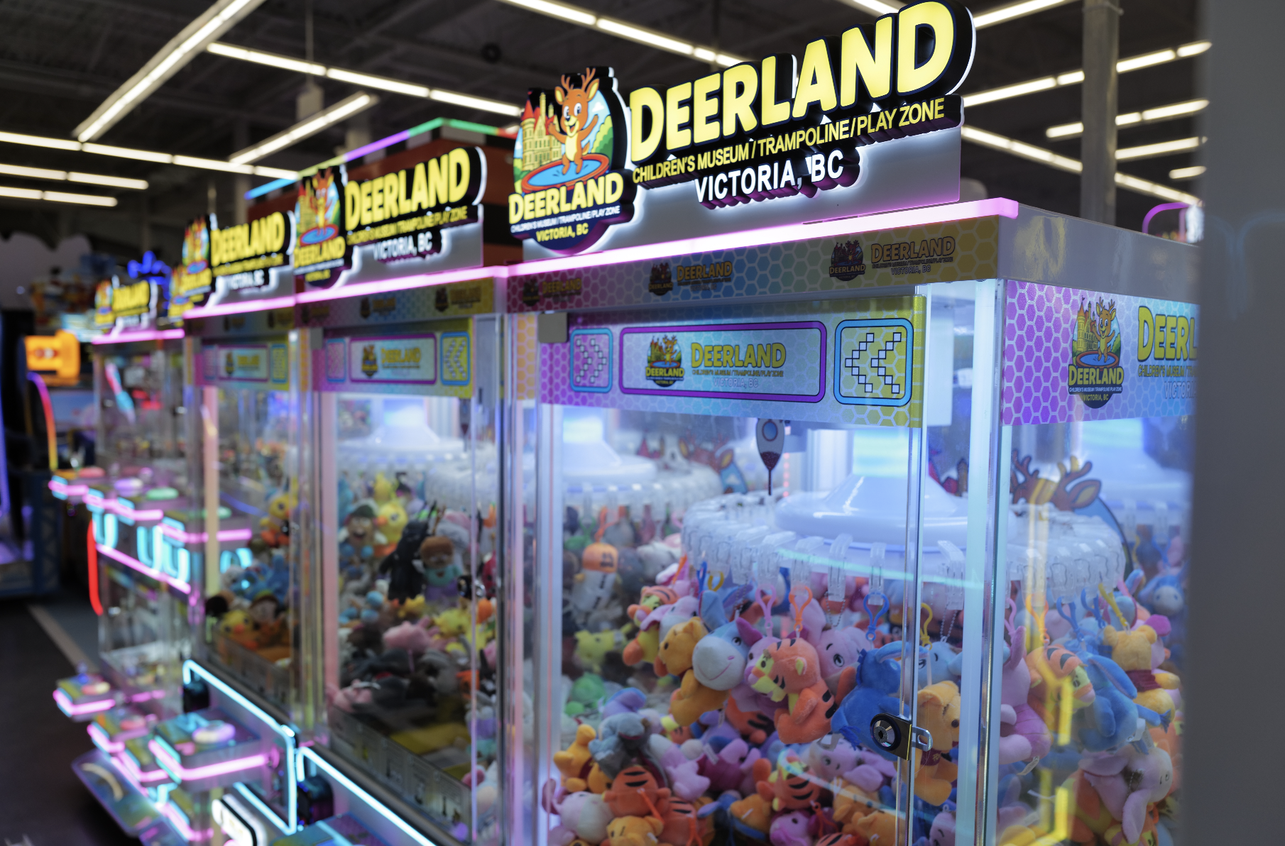 Deerland-branded claw machine row with plush prizes